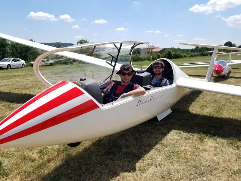 Un passager et son pilote, souriants dans le cockpit d'un planeur biplace