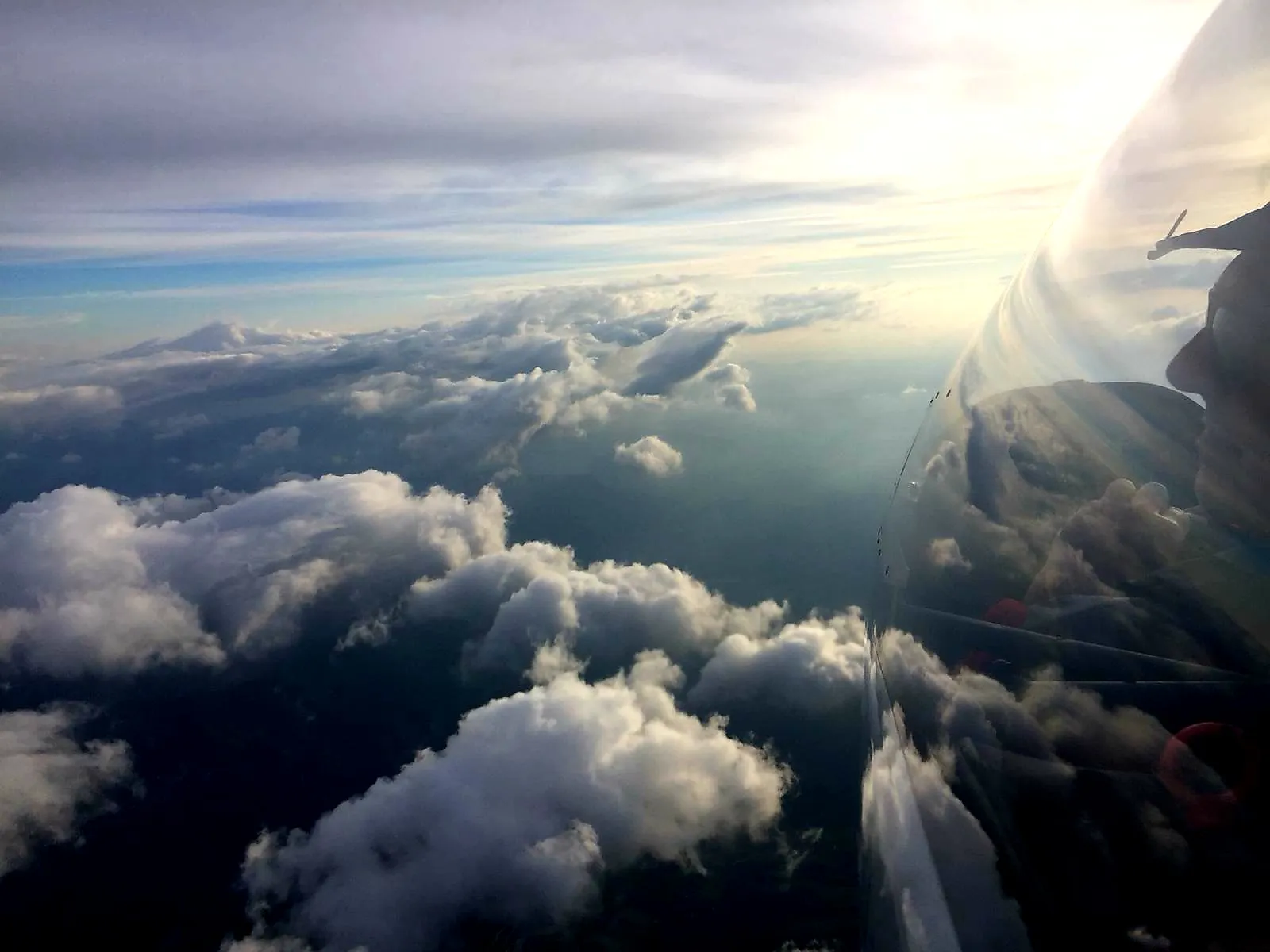 Vue depuis le cockpit d'un planeur au-dessus d'une mer de nuages, au soleil couchant